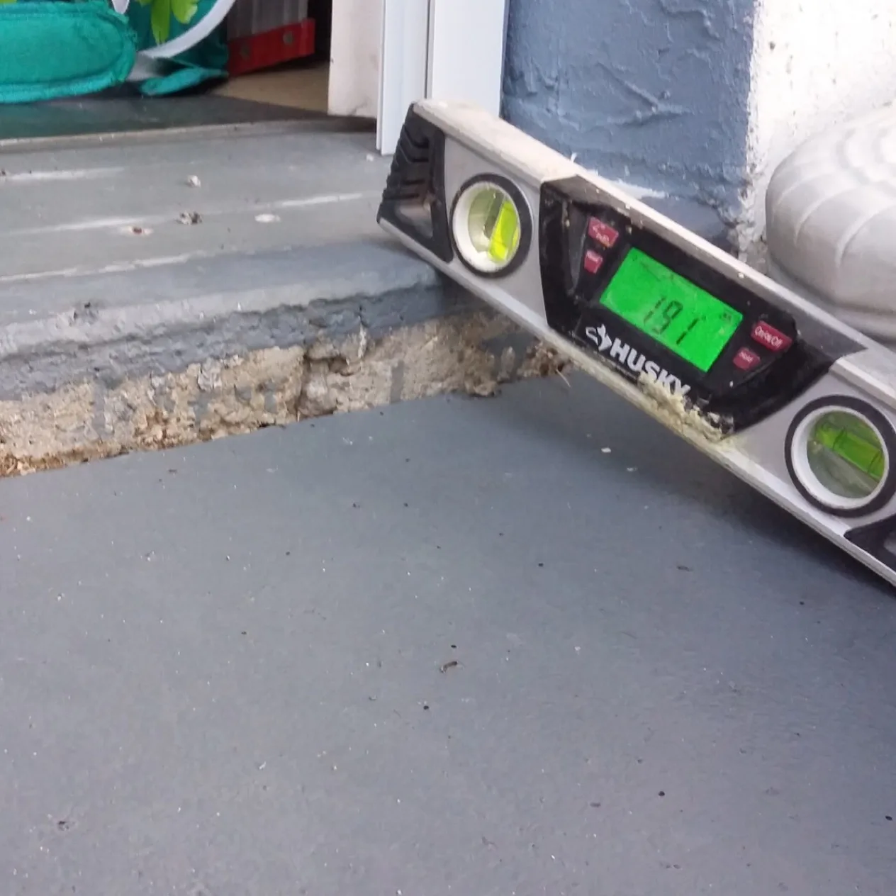 Measuring a sunken driveway at a garage entrance before concrete leveling