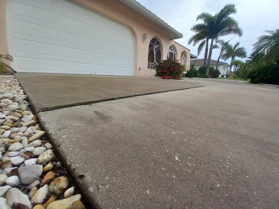 Sunken concrete driveway with uneven slabs and raised joint