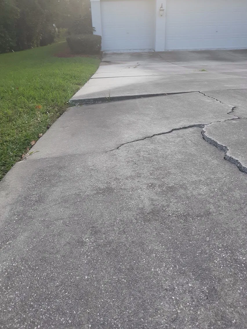 Sunken concrete driveway with uneven slabs and cracking in Tampa Bay Florida