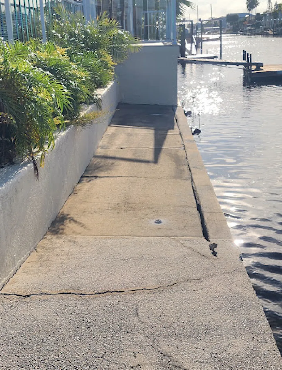 Soil loss and unsupported concrete walkway along a seawall in Florida